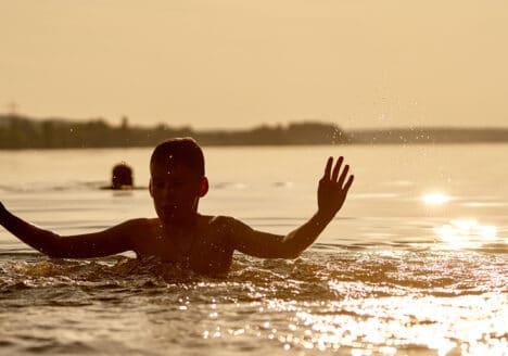 ein Mann ist im Wasser und geniesst das Wetter bei einem Sonnenuntergang